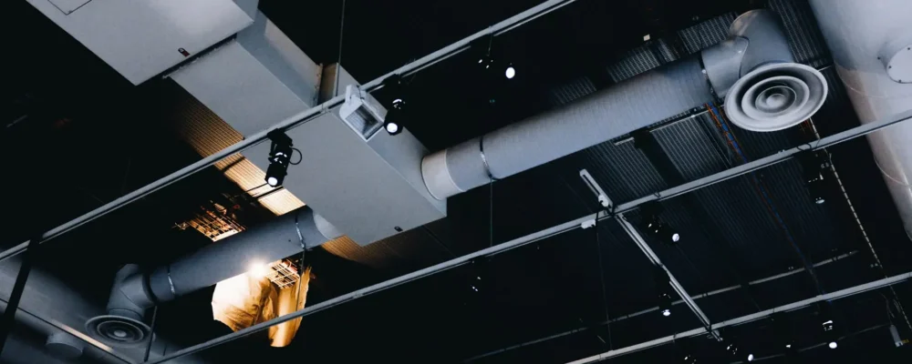 A low angle shot of a metal black ceiling with white ventilation pipes